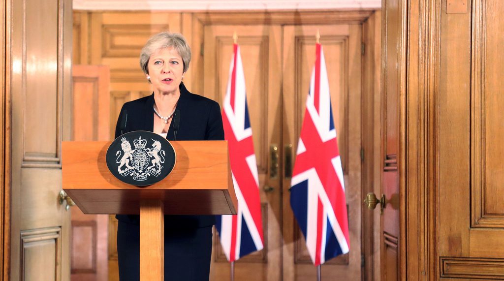 Theresa May, British PM, at a podium in front of two British flags