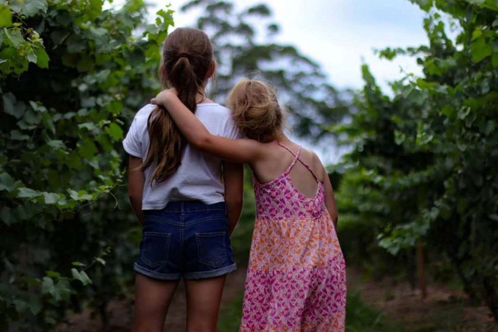 A young girls puts her arm around another young girl